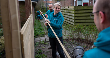 Medewerkers De Friesland, Alexander, Carmen en Eelco die samen een schutting aan het vastzetten zijn.