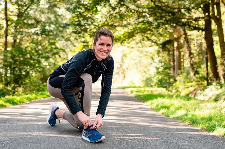 Else Lokhorst strikt de veters van haar hardloopschoenen in het bos
