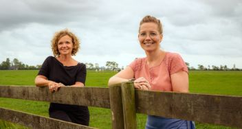 Jacqueline Vissers en Henderika Terpstra-Sieperda leunen op een hek in een weiland
