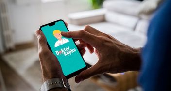 Persoon heeft smartphone vast en bekijkt het beginscherm van Dokter Appke. Op het beginscherm staat het beeld en het logo van Dokter Appke.